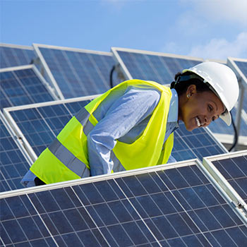 Solar panels being looked at by a smiling black female worker