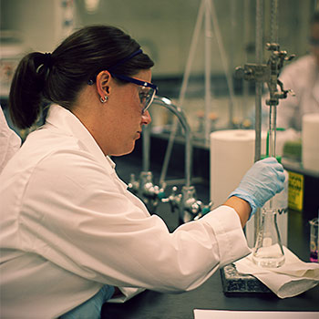 Chemicals being held by a female in a white lab