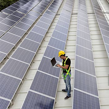 An array of solar panels with a male solar project manager