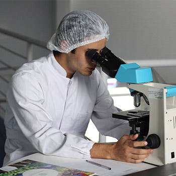 Man looking through a microscope while wearing a white lab coat