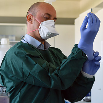 Man putting on rubber gloves while wearing a medical mask